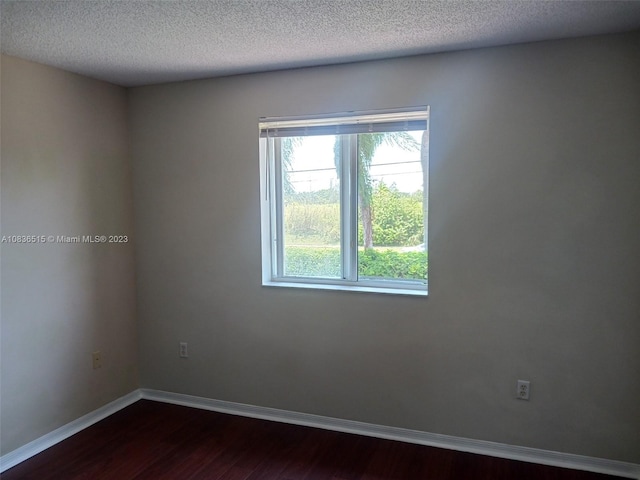 spare room with dark hardwood / wood-style floors and a textured ceiling