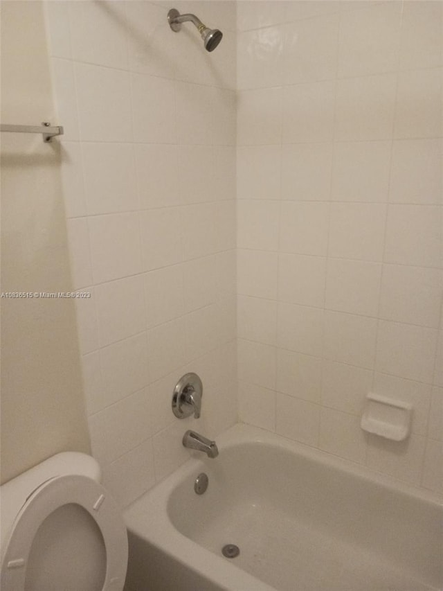 bathroom featuring tiled shower / bath combo and toilet