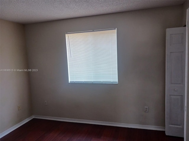 unfurnished room with a textured ceiling and dark hardwood / wood-style floors