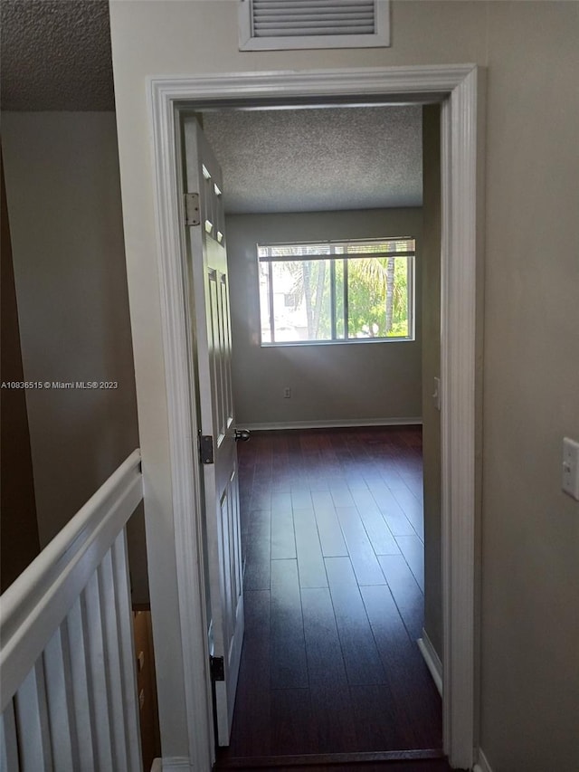 hallway featuring dark hardwood / wood-style flooring and a textured ceiling