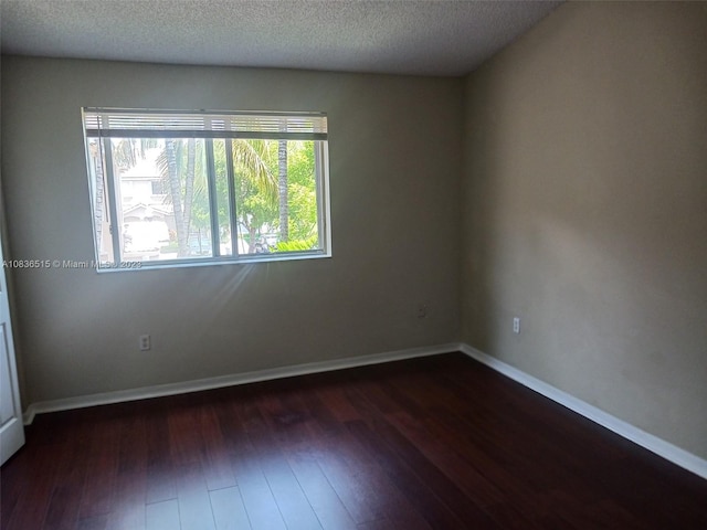 unfurnished room featuring a textured ceiling and dark hardwood / wood-style floors