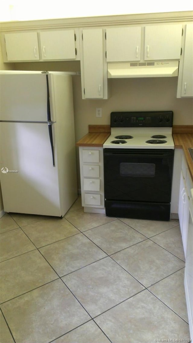 kitchen with cream cabinets, light tile patterned floors, wooden counters, and white appliances