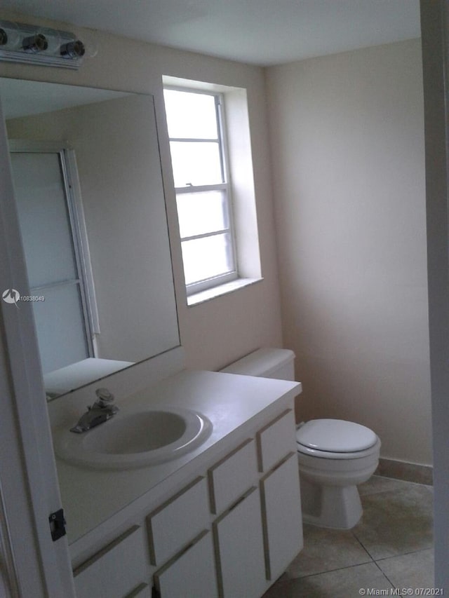 bathroom with toilet, vanity, and tile patterned floors