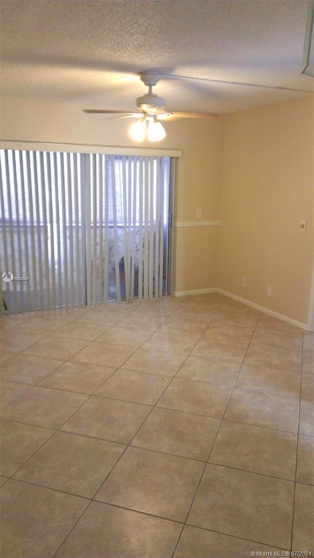 unfurnished room with ceiling fan, light tile patterned floors, and a textured ceiling