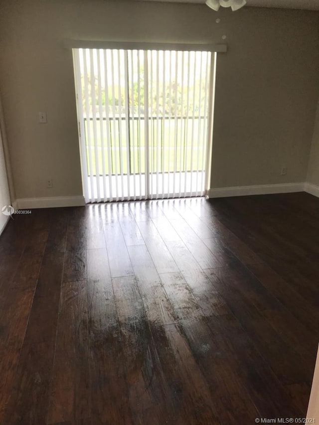 spare room featuring a wealth of natural light, dark wood-type flooring, and ceiling fan