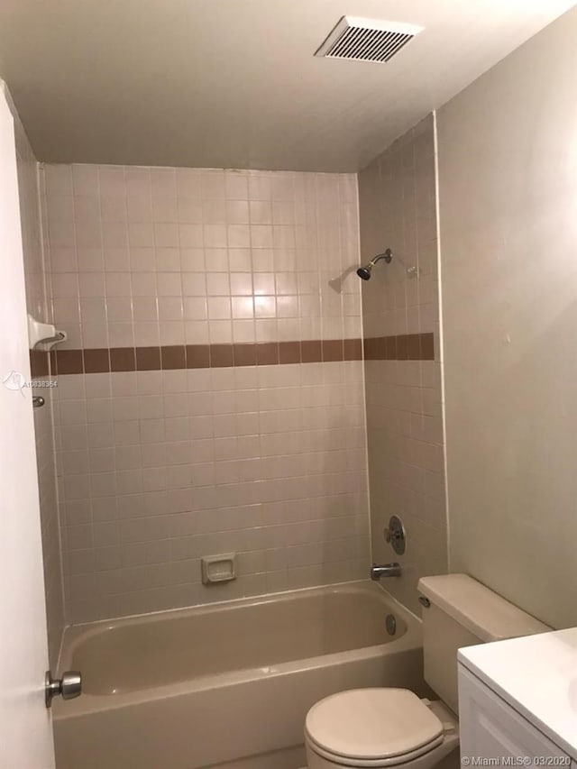 full bathroom featuring vanity, tiled shower / bath combo, and toilet