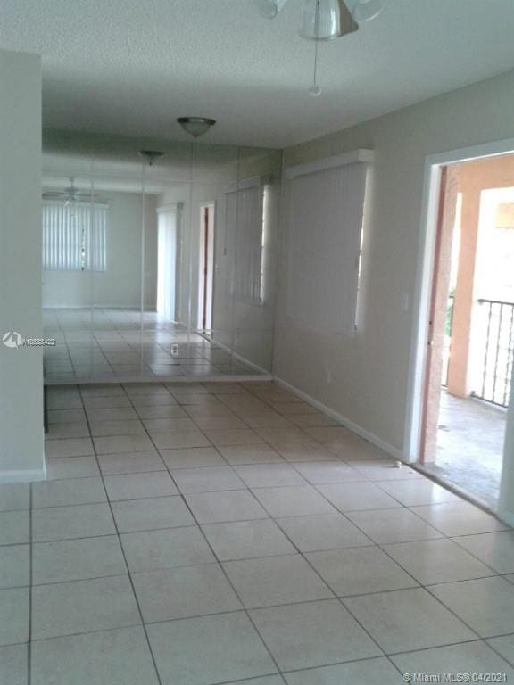 tiled empty room with a textured ceiling and ceiling fan