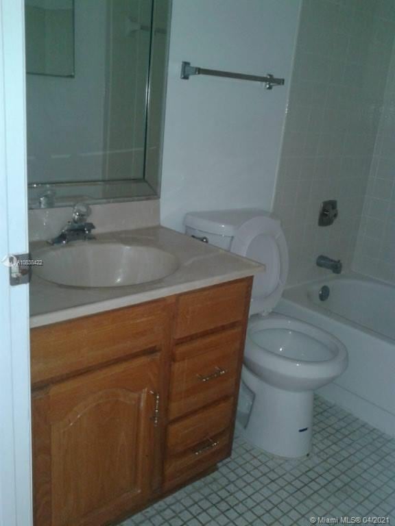 full bathroom with tile patterned flooring, vanity, tiled shower / bath combo, and toilet