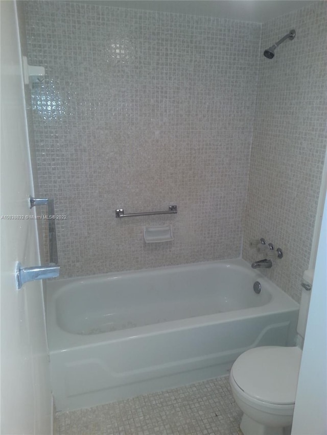 bathroom with tile patterned floors, tiled shower / bath combo, and toilet