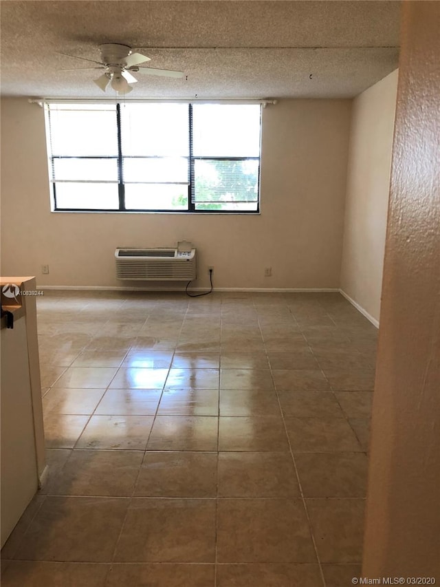 tiled spare room featuring ceiling fan, a textured ceiling, and a wall unit AC