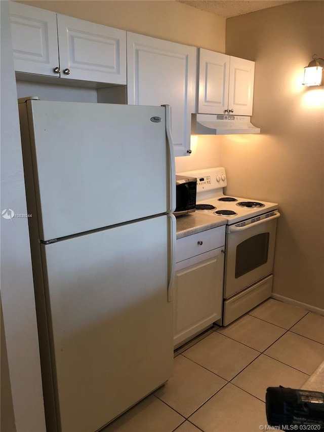 kitchen with white appliances, white cabinetry, and light tile patterned flooring