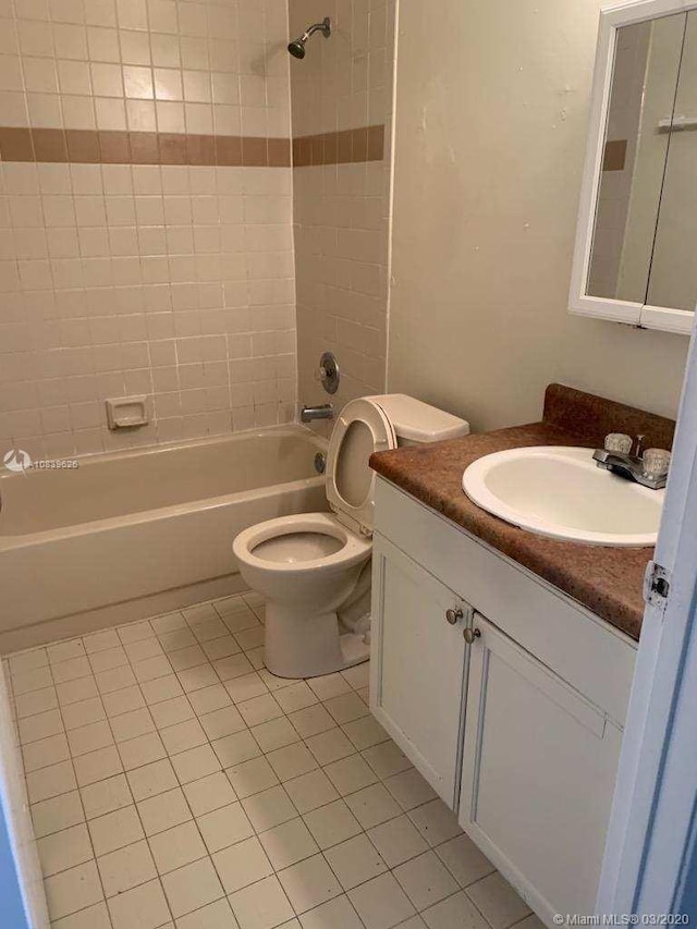 full bathroom featuring tile patterned flooring, vanity, tiled shower / bath combo, and toilet