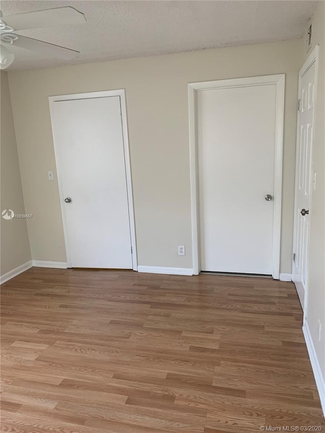 unfurnished bedroom featuring ceiling fan, light hardwood / wood-style flooring, and a textured ceiling