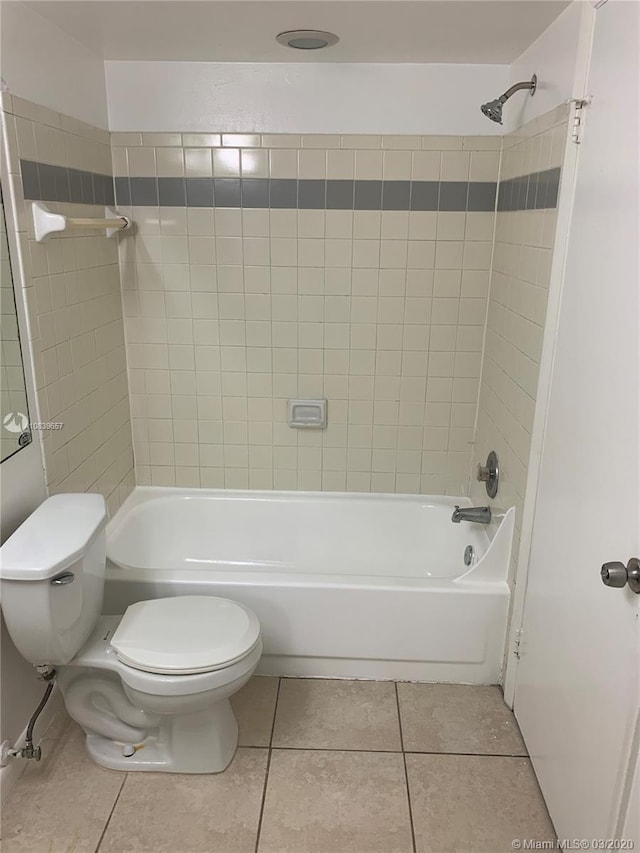 bathroom with tile patterned flooring, tiled shower / bath combo, and toilet