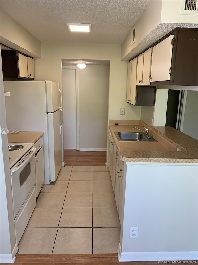 kitchen featuring white appliances, white cabinets, sink, a textured ceiling, and light tile patterned flooring