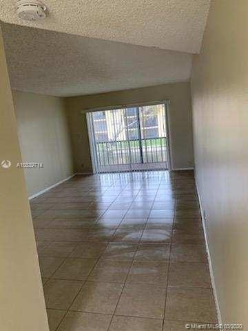 tiled empty room featuring a textured ceiling