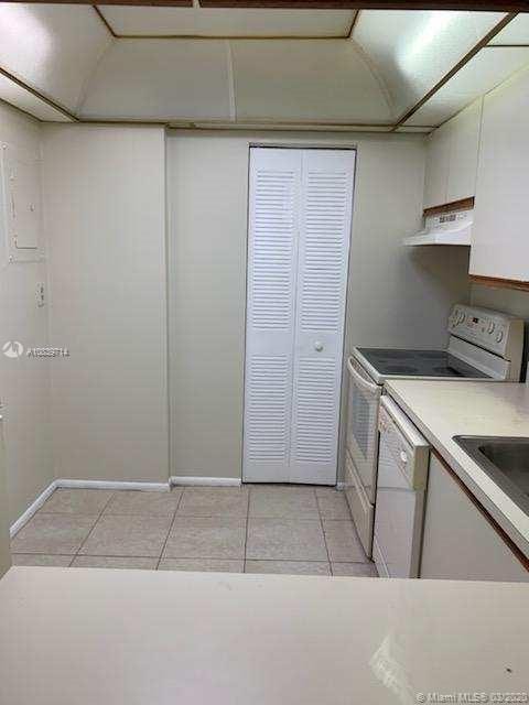 kitchen with white cabinets, light tile patterned floors, and white appliances