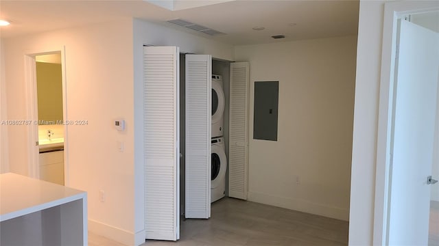 corridor featuring stacked washer / drying machine, wood-type flooring, and electric panel