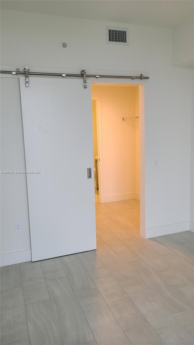 tiled empty room featuring a barn door