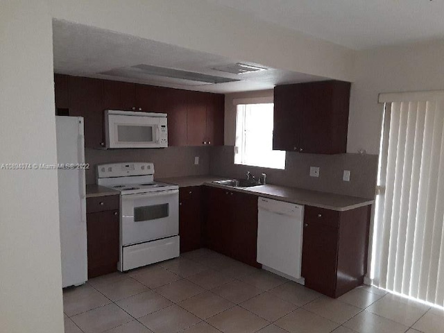 kitchen featuring dark brown cabinetry, sink, white appliances, decorative backsplash, and light tile patterned floors