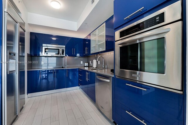 kitchen featuring stainless steel counters, stainless steel appliances, blue cabinets, and decorative backsplash