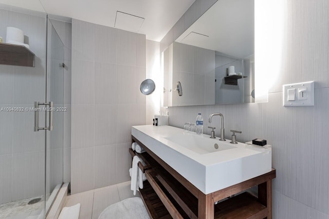 full bathroom with vanity, a shower stall, and tile walls