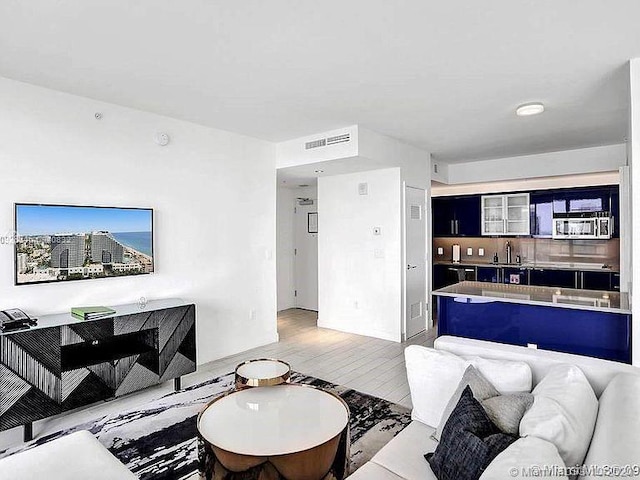 living area featuring light wood-style floors and visible vents