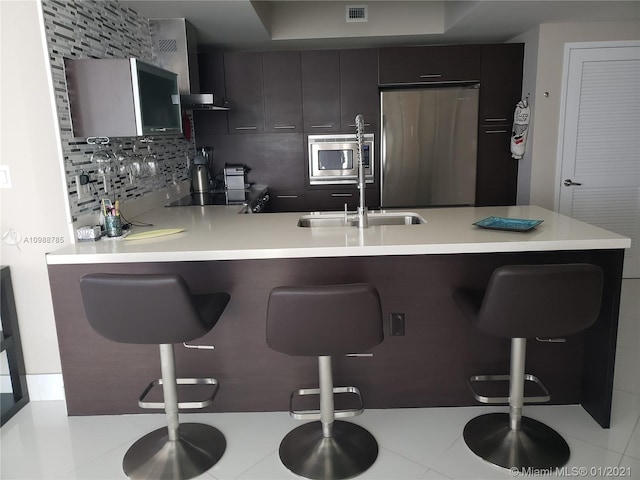 kitchen featuring backsplash, a kitchen breakfast bar, kitchen peninsula, and appliances with stainless steel finishes