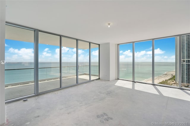 empty room with a water view, concrete floors, and a wall of windows