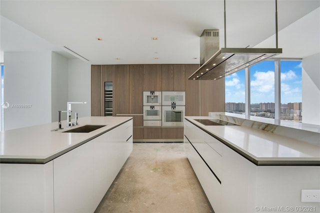 kitchen featuring extractor fan, white cabinetry, an island with sink, and sink