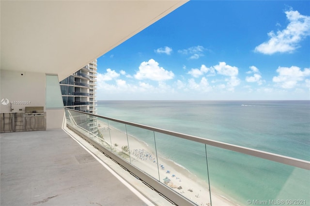 balcony featuring area for grilling, a water view, and a view of the beach