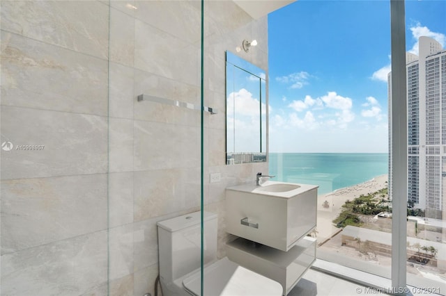 bathroom featuring tile walls, a beach view, a water view, and a healthy amount of sunlight