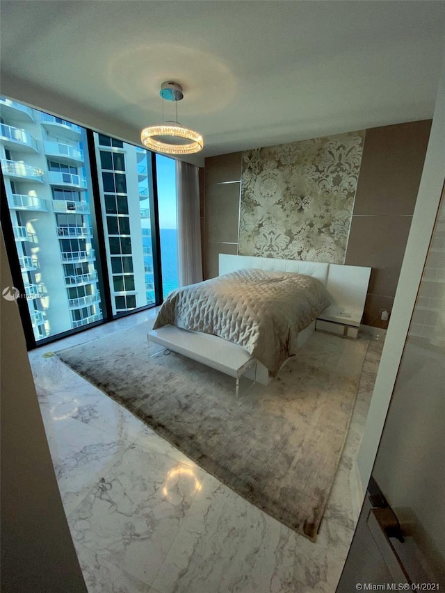 bedroom featuring expansive windows, access to exterior, and a water view