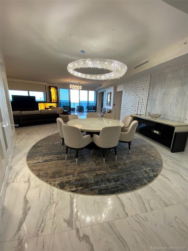 tiled dining space featuring a raised ceiling and a chandelier