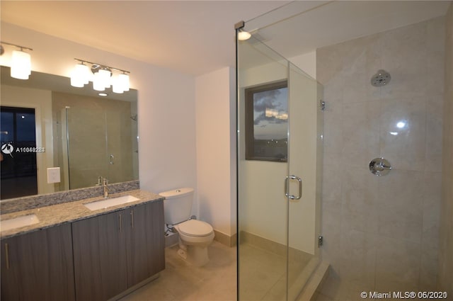 bathroom featuring a shower with shower door, double vanity, toilet, and tile floors