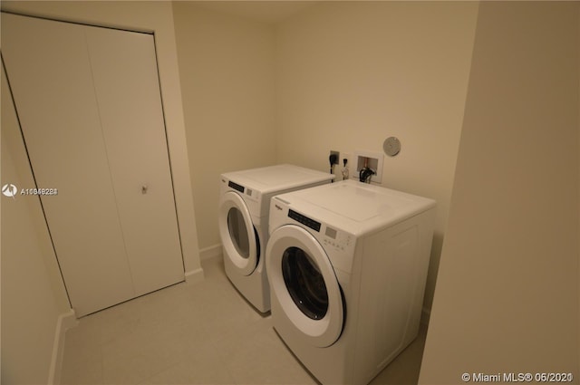 clothes washing area with electric dryer hookup, washer hookup, light tile flooring, and washing machine and dryer