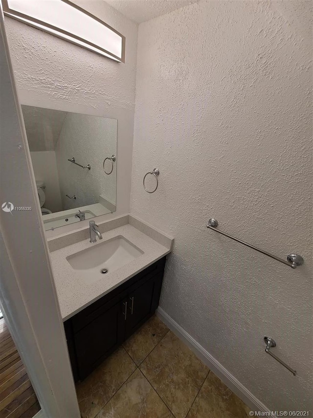 bathroom with tile patterned flooring, vanity, and toilet