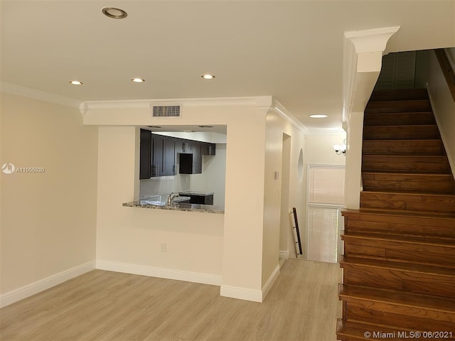 unfurnished living room featuring hardwood / wood-style flooring, sink, and crown molding