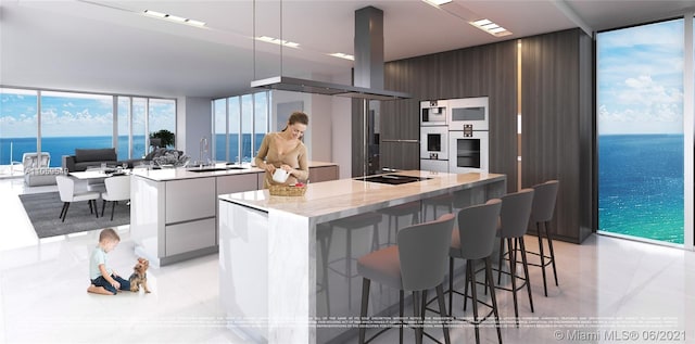 kitchen featuring black electric stovetop, a water view, a center island, and expansive windows