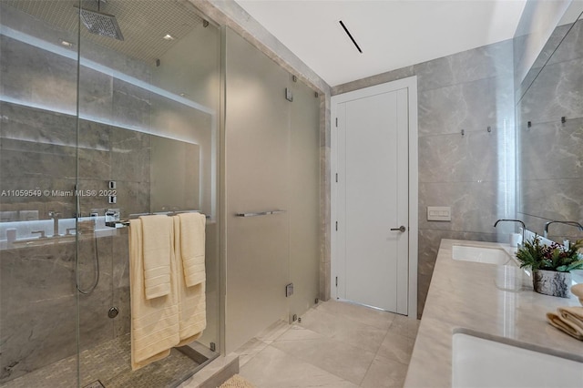 bathroom with tile walls, sink, and a shower with shower door