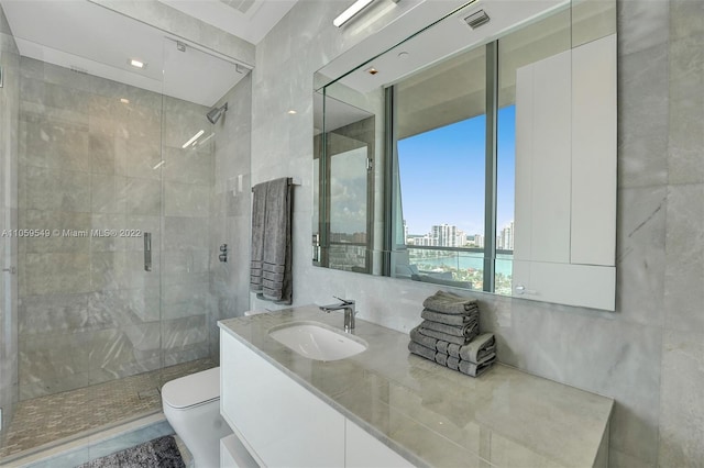 bathroom featuring tile walls, a shower with door, vanity, and toilet