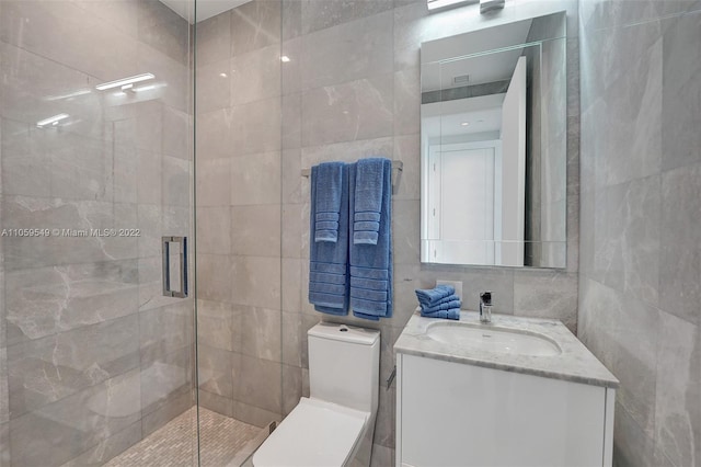 bathroom featuring tile walls, a shower with shower door, vanity, and toilet