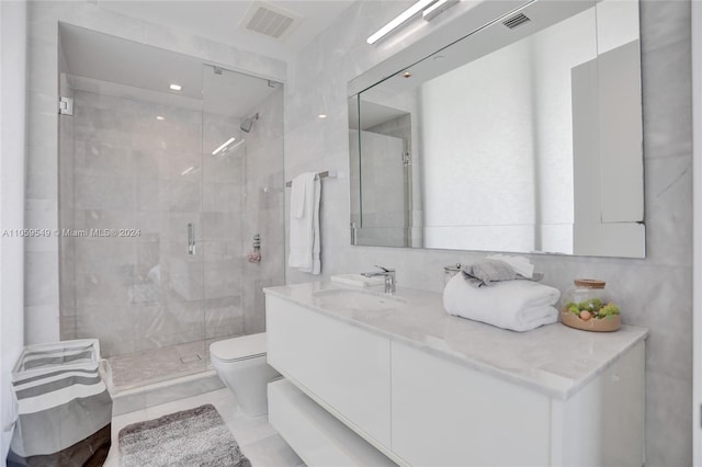 bathroom featuring tile walls, vanity, toilet, and a shower with door