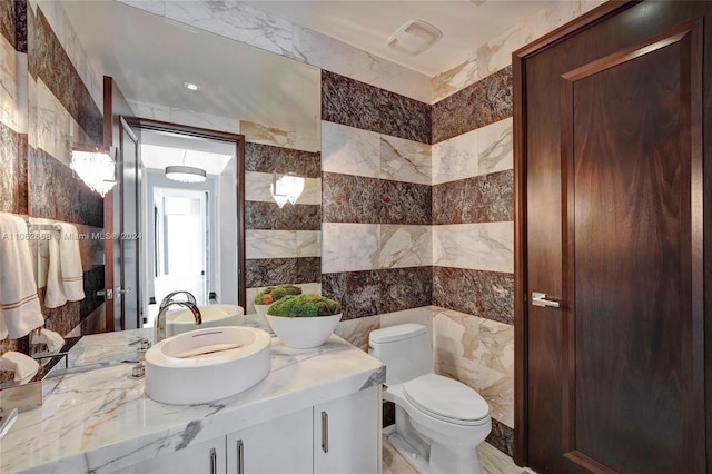 bathroom with vanity, tile walls, and toilet