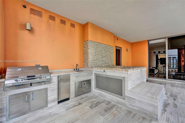 kitchen with decorative backsplash, light hardwood / wood-style floors, sink, and stainless steel fridge