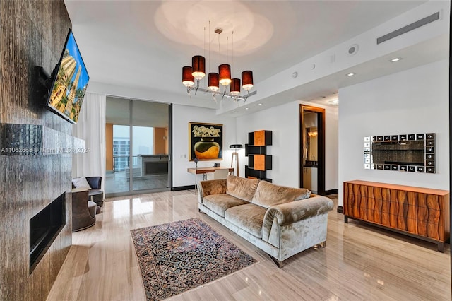 living room featuring light wood-type flooring, a fireplace, and a notable chandelier