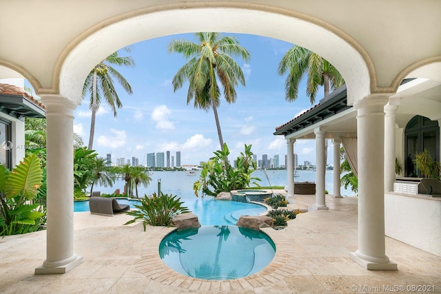 view of pool featuring an in ground hot tub, a patio, and a water view