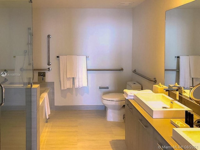 full bathroom with toilet, vanity with extensive cabinet space, hardwood / wood-style flooring, and separate shower and tub