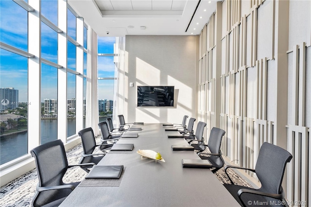 gym with french doors, a wall of windows, a tray ceiling, a high ceiling, and a water view