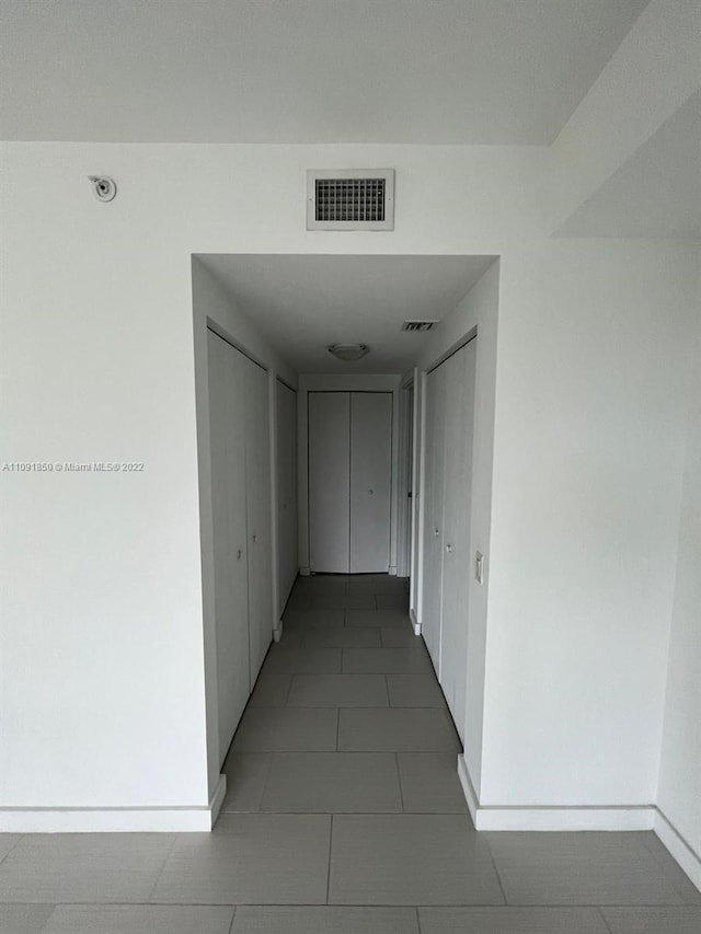 hall featuring dark tile flooring